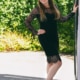 Sophia- VIP Escortmodel Berlin an der offenen Terassentür im schwarzen Kleid mit Spitze.