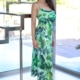 Alexandra - Elite Escort Frankfurt im langen grünen Sommerkleid mit High Heels vor einer Glastreppe stehend.