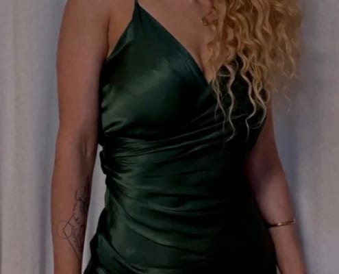 Aurlie - Escort Bonn mit lockigem Haar und einem grünen Kleid.