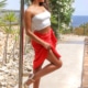 Adriana - Escort Köln im sommerlichen Outfit aus Rocke und Top vor dem Pool stehend.